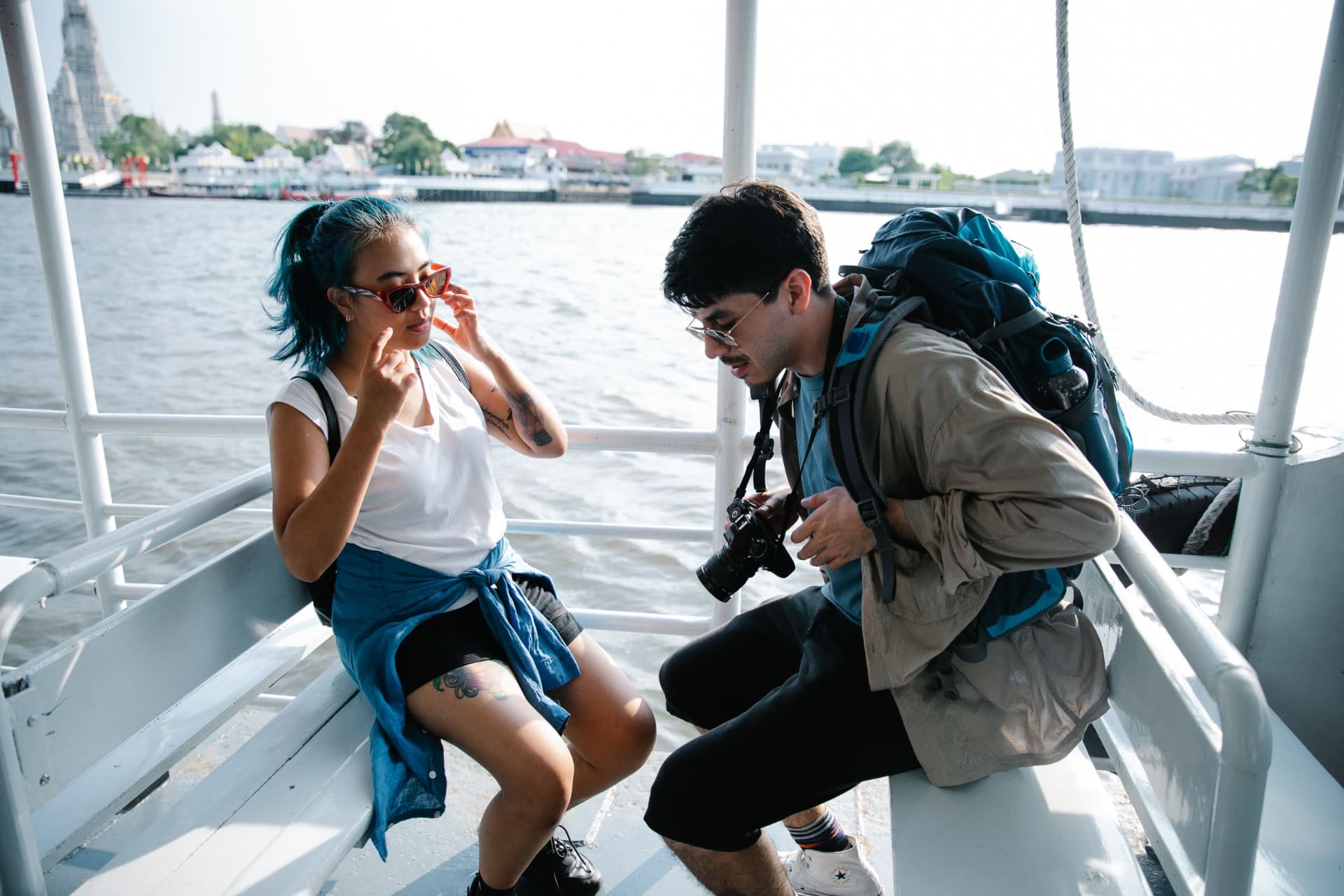 Two travellers sitting on a ferry deck, laughing together.