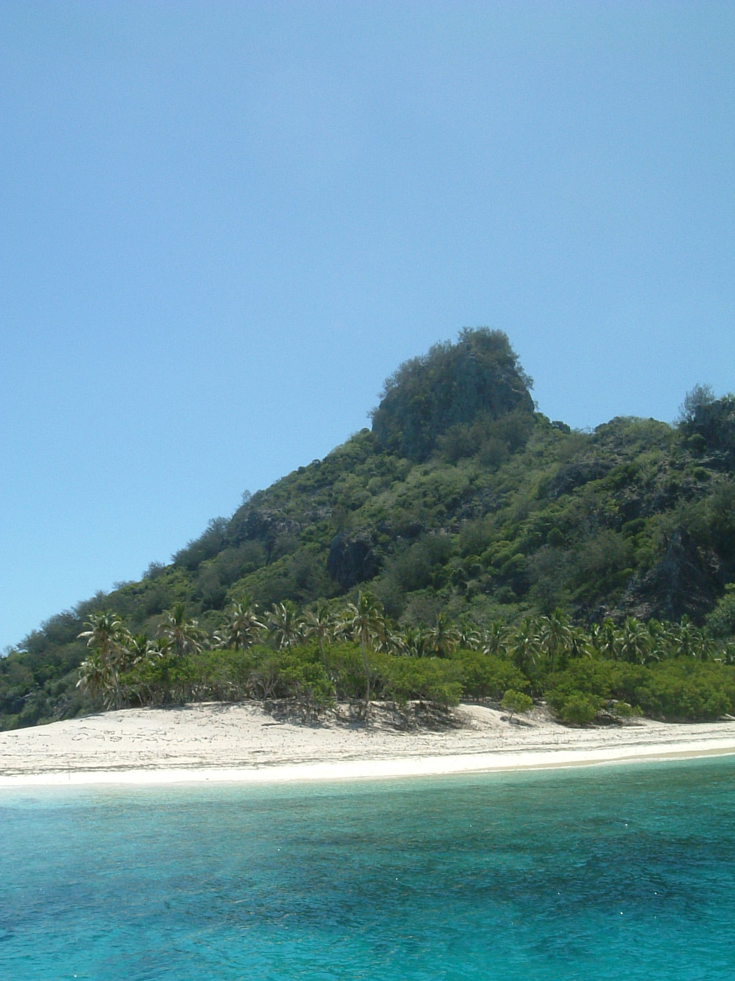 The green peak of Monuriki rising above palms and a turquoise lagoon.